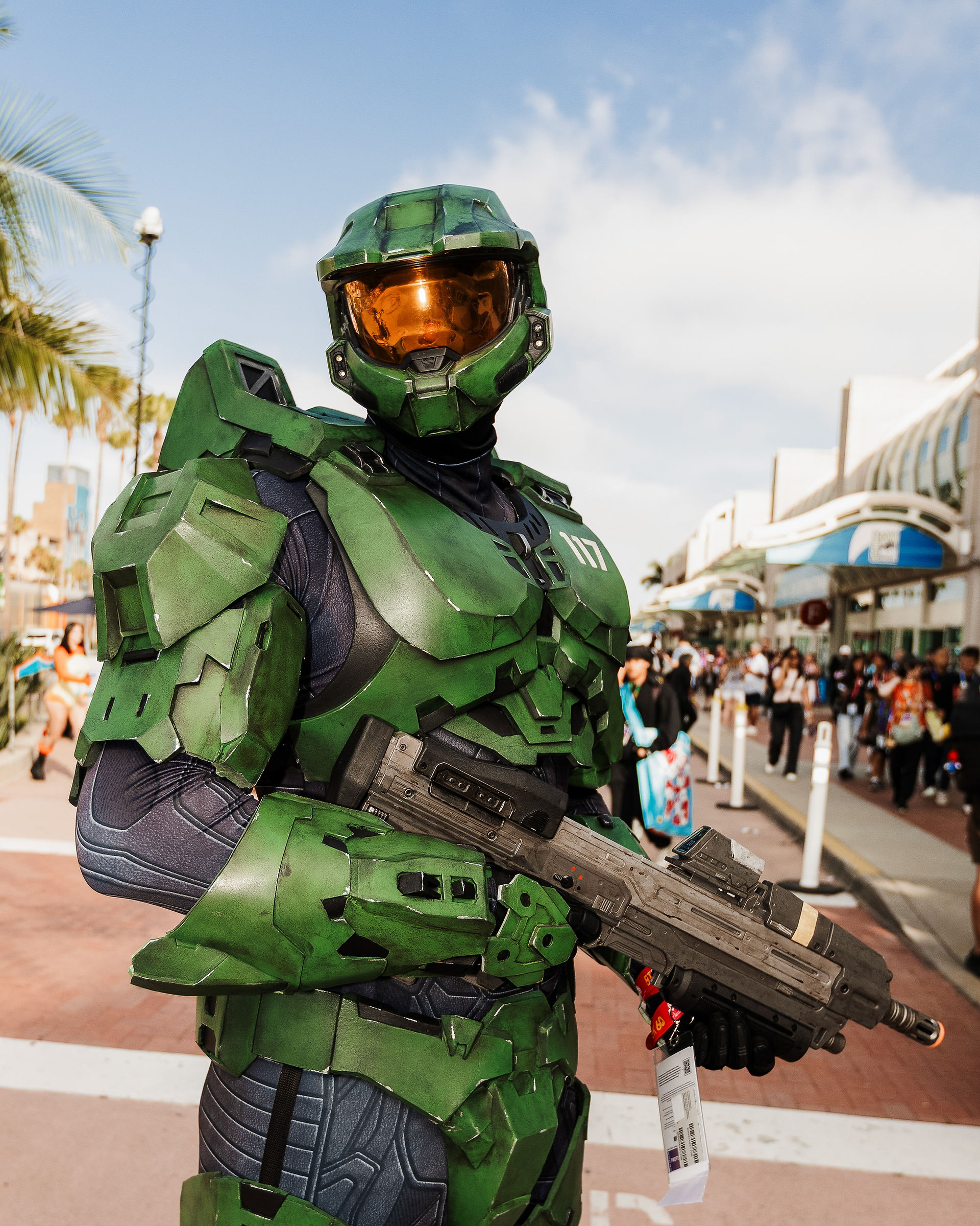 Portrait of @ahsumm1 dressed as Master Chief from the Halo video game series outside the San Diego Convention Center during San Diego Comic-Con 2026, wearing green Mjolnir armor with a gold visor and holding a UNSC rifle.