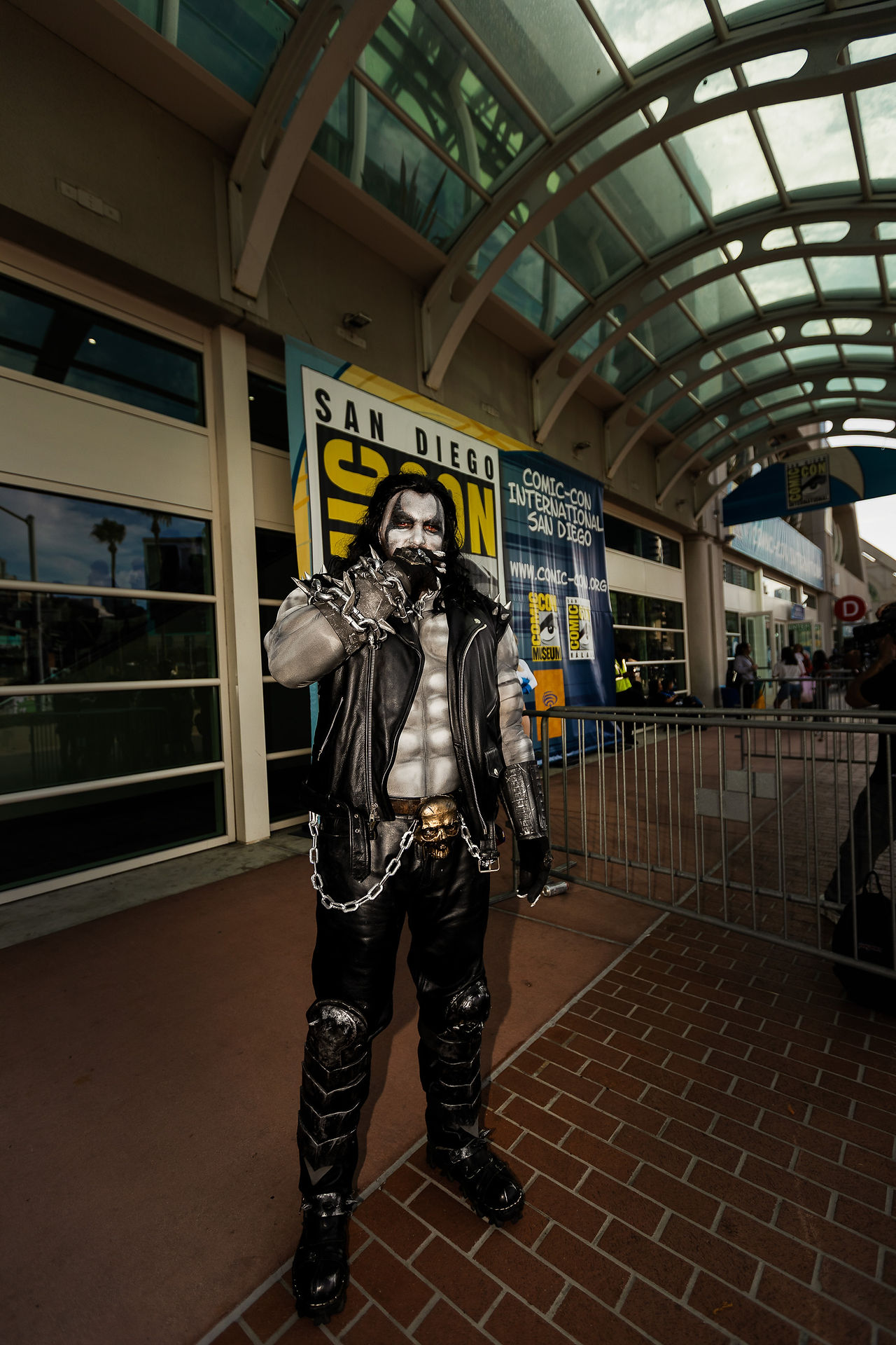 Full body portrait of @aquaman__sd dressed as Lobo from DC Comics outside the San Diego Convention Center during San Diego Comic-Con 2026, wearing detailed body paint, spiked leather armor, heavy chains, and holding a cigar.
