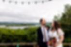Wedded couple smile at each other with Chew Valley Lake in background