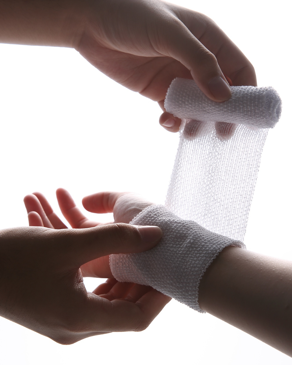 A person wrapping another person's hand in a bandage