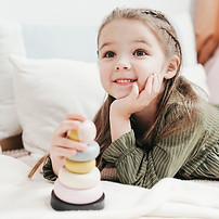 A young girl smiling with a donut stack toy