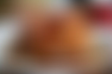 Stack of pancakes topped with crispy bacon, walnuts, and syrup on a white plate. A fork and a cup in the background. Warm, appetizing mood.