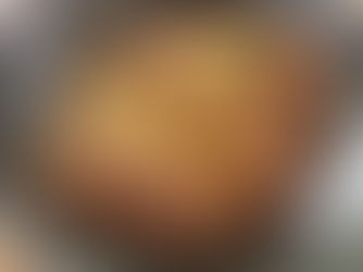 A bowl of STRONCATURA pasta topped with breadcrumbs, herbs, and a red chili pepper sits on a patterned table. The dish appears savory and inviting.