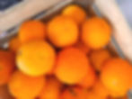 A wooden crate filled with vibrant, fresh oranges. The bright orange color dominates, creating a lively, fresh mood.