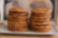 Two tall stacks of golden-brown pancakes on a white plate, set against a neutral background with soft, warm lighting.