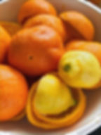 Oranges and one lemon with peels sit in a white bowl. The vibrant colors create a fresh and lively mood.