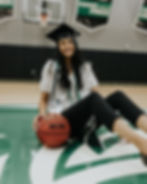 Nehaa holding a basketball wearing her graduation regalia