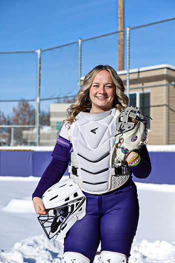 Hailee in her catcher's uniform standing outside