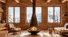 Interno di uno chalet in legno con camino centrale e ampie finestre affacciate sulle montagne innevate.