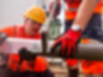Two workers cutting pipe with a tool