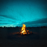 A warm beach campfire under a mystical teal sky featuring tree and mountain silhouettes in the Sacred Rat style
