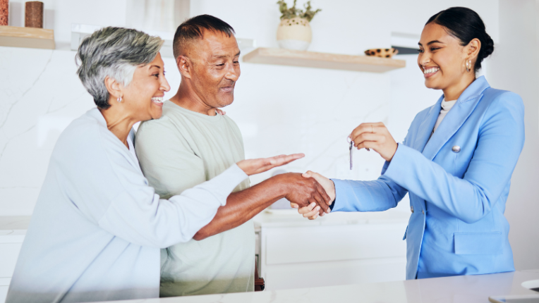 Happy retired couple being handed keys from a real estate agent