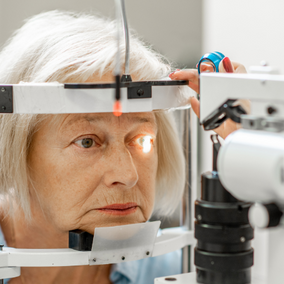retired woman getting an eye exam with bright light in her left eye