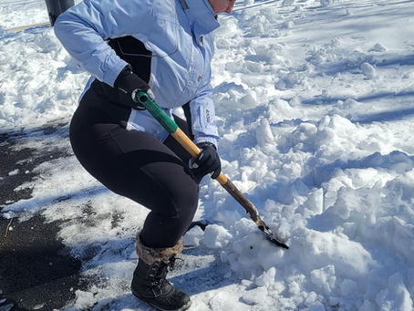 Woman shoveling snow with proper form to avoid back and neck pain