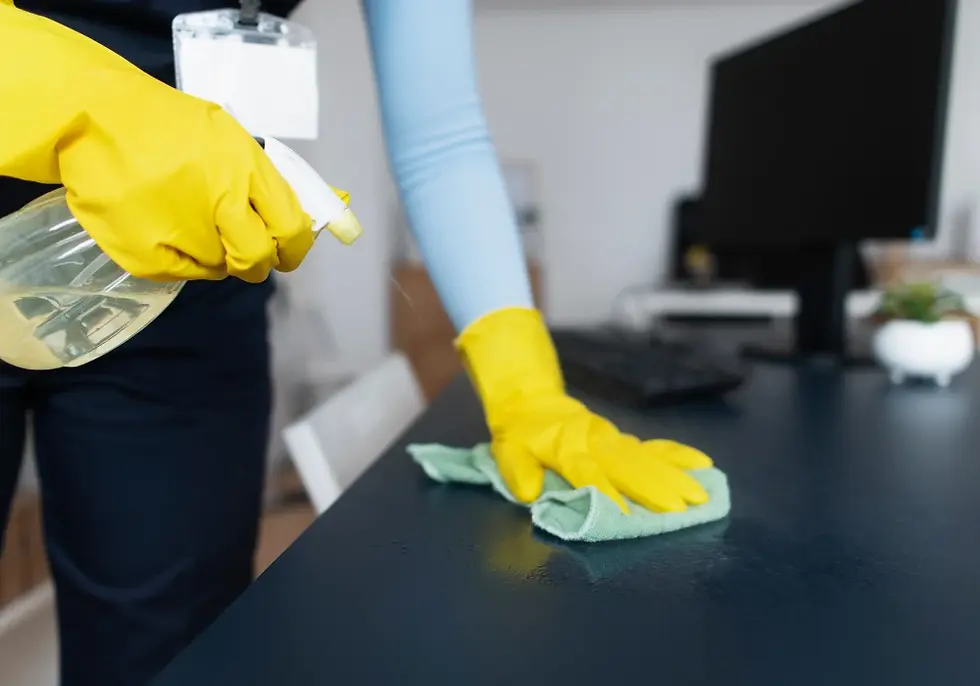 A person cleaning the surface of an office table