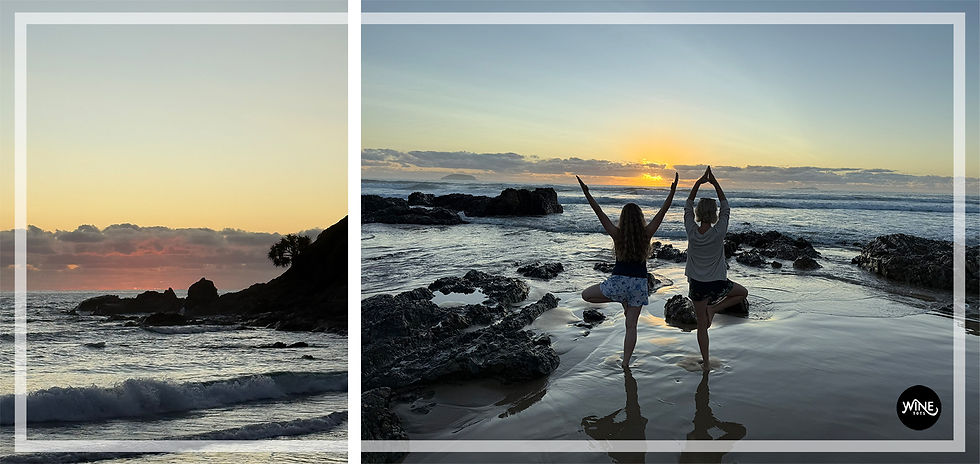 Two people doing yoga on Moonee beach at sunset, silhouetted against the sky. Waves and rocks surround them. Calm, serene atmosphere.