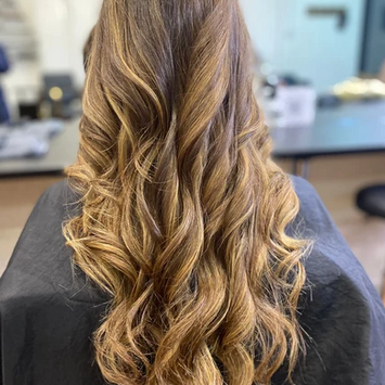 Long, softly curled hair with natural-looking balayage highlights, styled by Charlie.