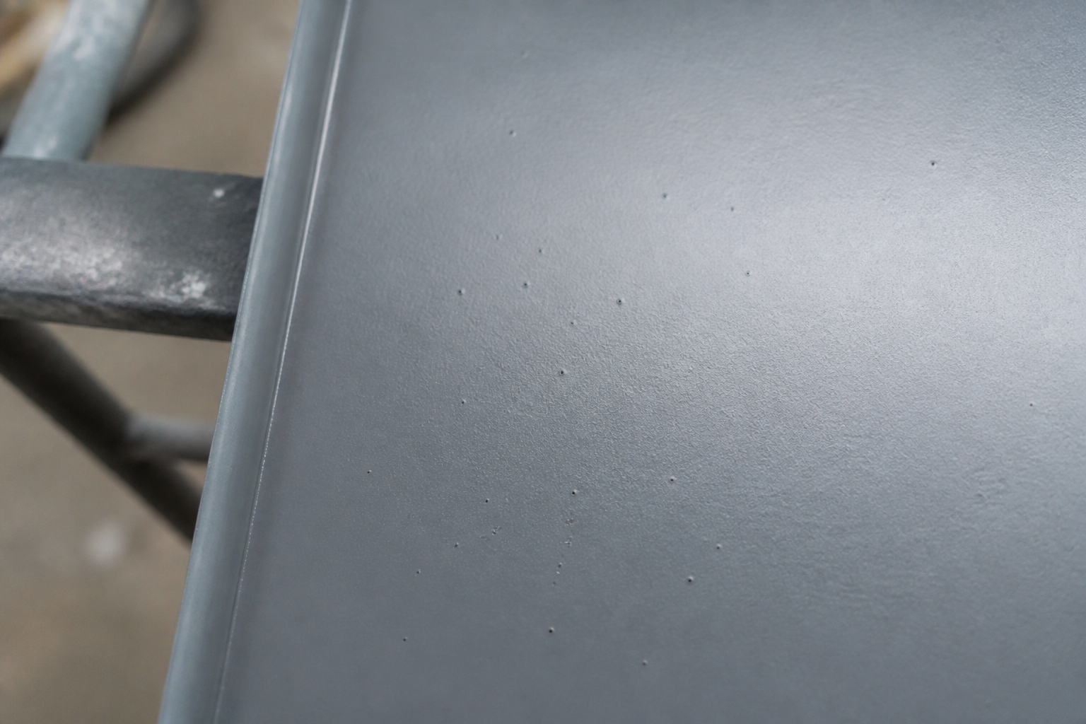Why are tiny pinholes forming in a sprayed metal coating?