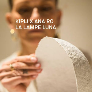 lampe Luna en premier plan, conçue pour Kipli avec Ana Ro en arrière plan flou effectuant un contrôle de qualité.