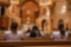 View of people sitting in a Catholic church looking toward the Eucharist on the altar