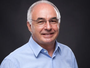 homem com cabelos brancos, óculos e camisa azul