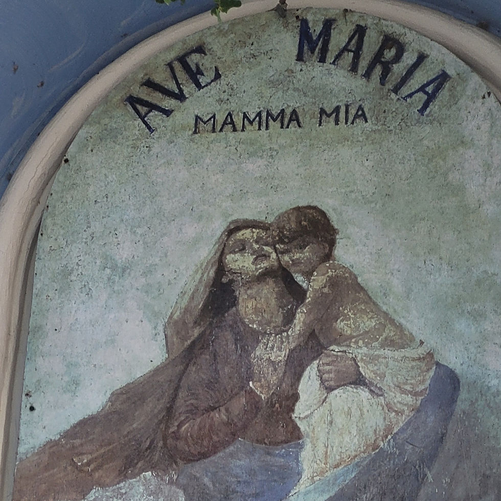 Weathered mural of Mary and child hugging, with Ave Maria and MAMMA MIA text on a pale blue wall, devotional and worn.