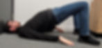 A man lying on his back with his knees bent. He has lifted his pelvis in the air so there is a straight line between his knees and his shoulders.