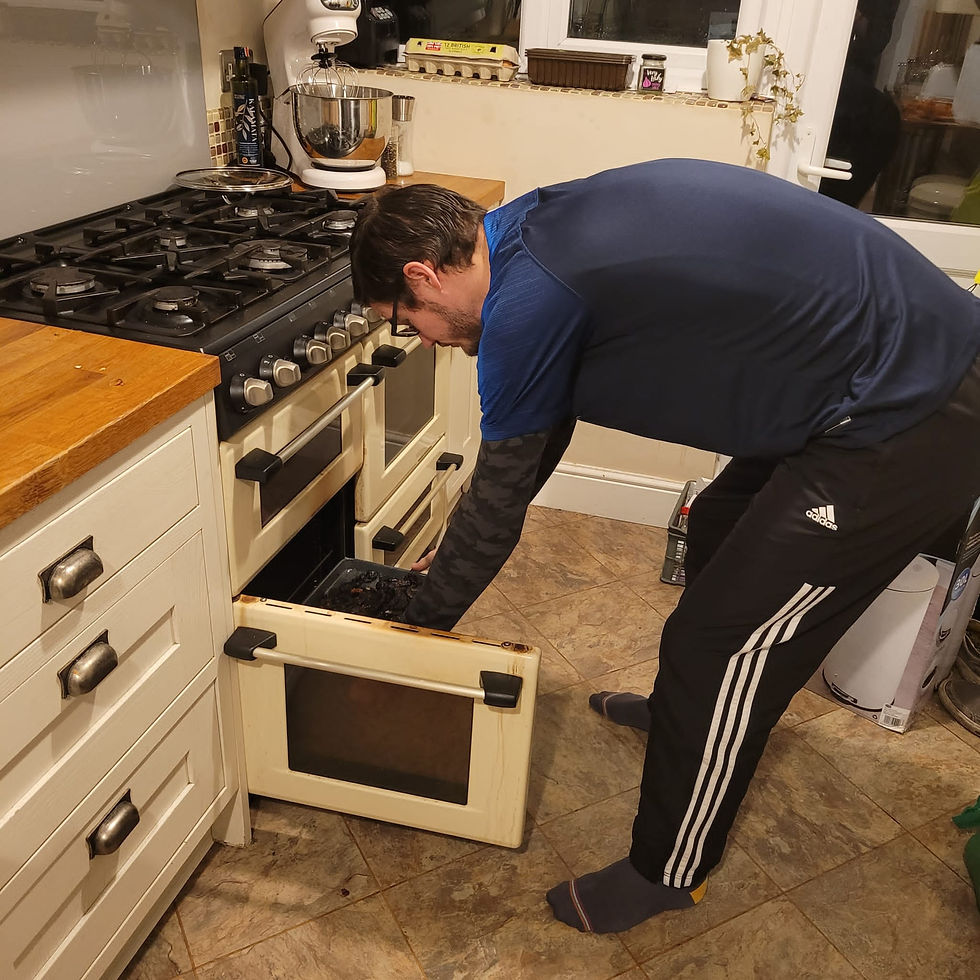 A man putting a tray in the oven from the side. He has not bent his knees and is therefore rounding his back to be able to reach.