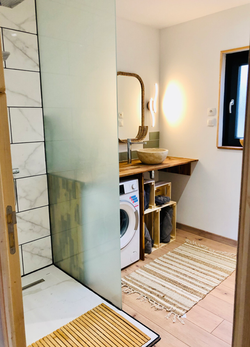 Le Chaleureux : la salle d'eau avec douche à l'italienne, machine à laver, vasque et sèche serviette