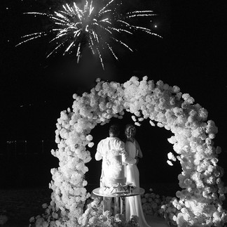 Black-and-white Montenegro wedding photography of celebrity bride Nadja Kljajic and groom under floral arch watching fireworks at One&Only Portonovi – luxury editorial wedding photography