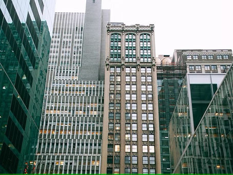Tall skyscrapers in a cityscape, reflecting in glass buildings. Overcast sky. Traditional and modern architecture blend seamlessly.