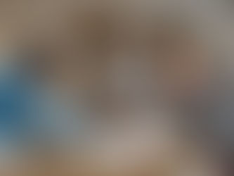 Two men shake hands across a cluttered table, papers and money flying. A woman in a blazer smiles in the background. Office setting.