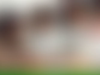 Colleagues in an office setting, smiling and collaborating at a table with laptops and notebooks, showcasing teamwork and focus.