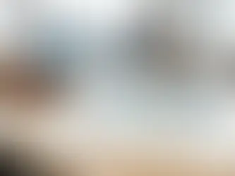 A Gantt chart titled "Quarterly Project Update" sits on a table. In the background, two people work on laptops in an office setting.