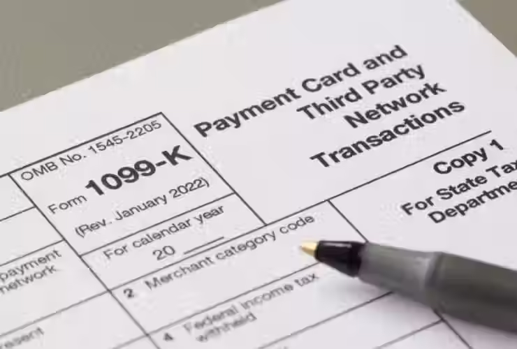 Close-up of a Form 1099-K titled “Payment Card and Third Party Network Transactions,” with a pen resting on the document near the calendar year and merchant category fields.