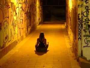 woman sitting peacefully in city tunnel with warm light shining down