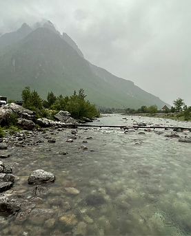 The Albanian Alps in the rain with a rocky river running through the center