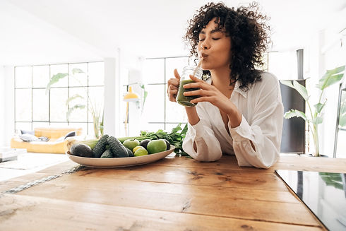 Young african american woman drinking green juice with reusable bamboo straw in loft apart