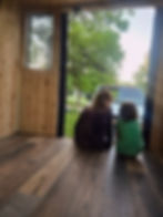 author's two children sitting at the back of the bus, looking out the rear exit on the new flooring