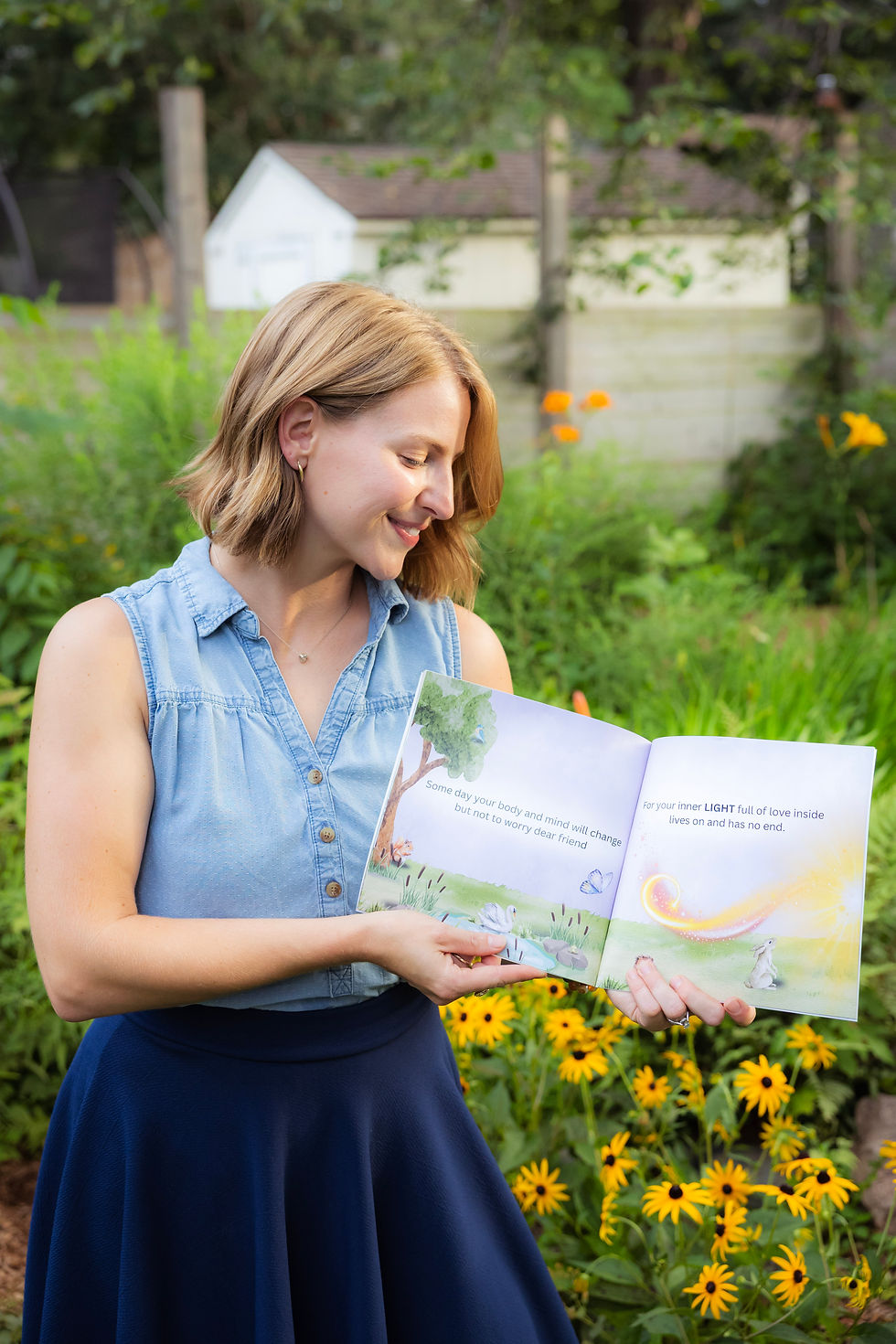 author Ashley Kay Andy smiling while reading her new children's book in a garden