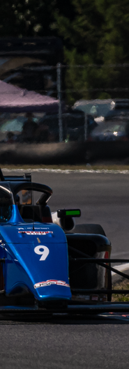 Ava Dobson driving a blue car on the racetrack during a competition.