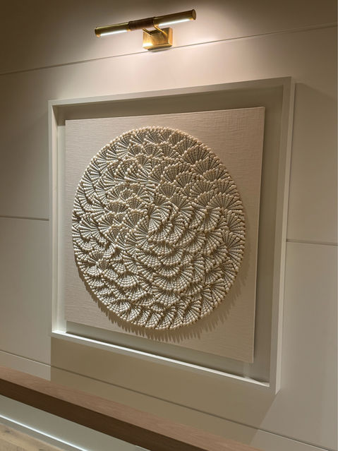 Shell artwork in a minimalist hallway on Nantucket Island, illuminated by an art light above