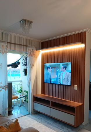 Painel ripado de madeira com home planejado em estilo moderno, com iluminação embutida em LED. Ambiente clean e sofisticado, com TV fixada no painel e móveis sob medida para a sala de estar.