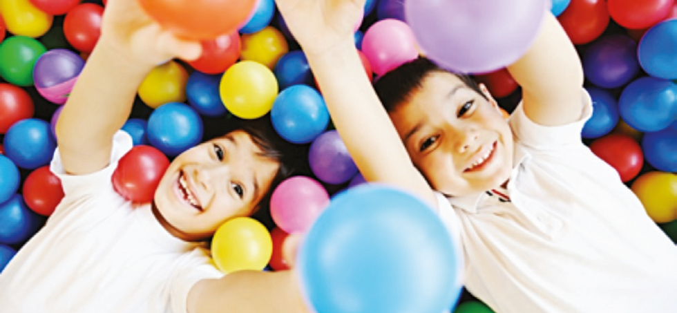 Image shows two boys playing in a ball pit.