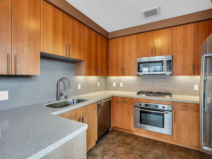 Modern kitchen with caramel colored wood cabinets and stainless steel appliances