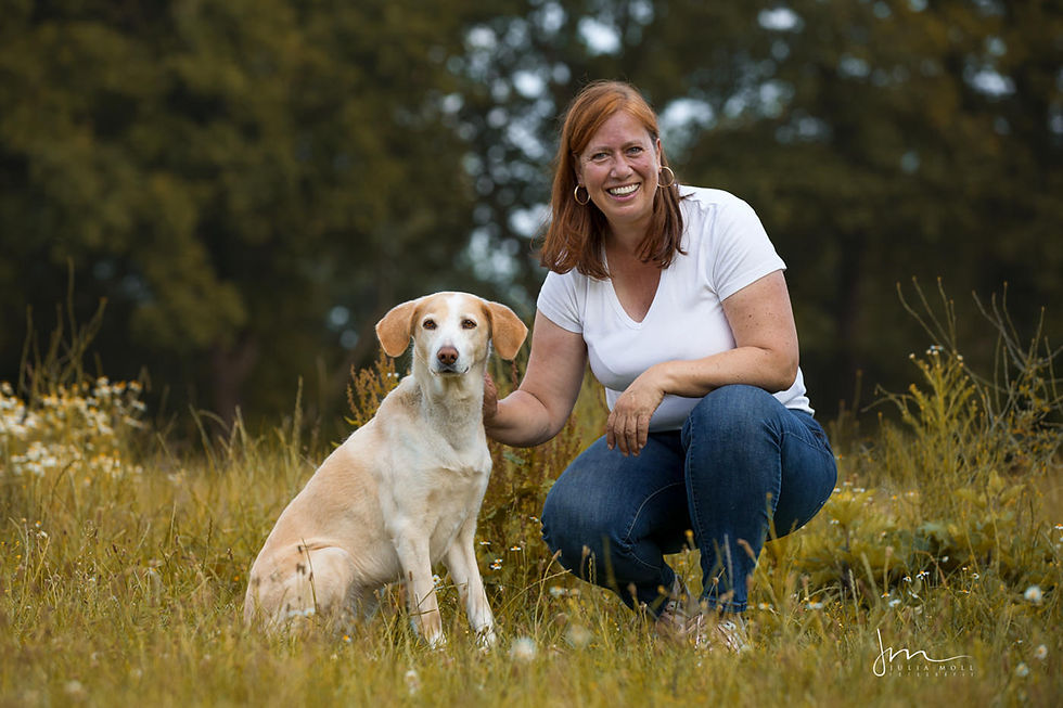 Katja Hammerschmidt sitzt mit ihrer Hündin Lotti auf einer sommerlichen Wiese