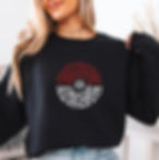Woman wearing a black sweatshirt with a red and white Poké Ball design made of character silhouettes, light background, casual mood.