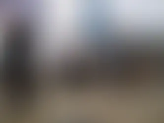 People walk on a busy city street with skyscrapers and cranes in the background. The mood is bustling under a partly cloudy sky.