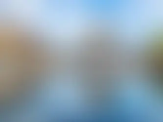 Historic building with a dome in a lively square. Reflection in water, colorful buildings, people walking, and blue sky backdrop.