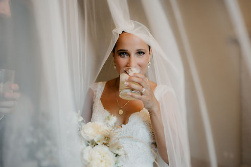 Bride enjoying a signature cocktail under her veil during an elegant wedding